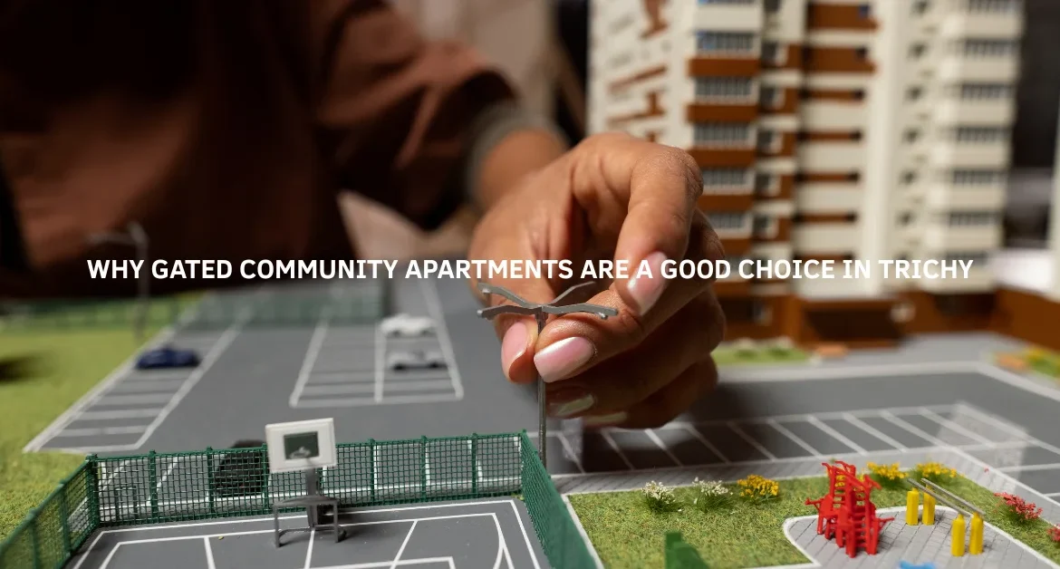 Close-up of a person placing a miniature streetlight on a detailed model of a gated apartment complex, featuring play areas, parking spaces, and high-rise buildings, symbolizing the planning and benefits of gated communities in Trichy.